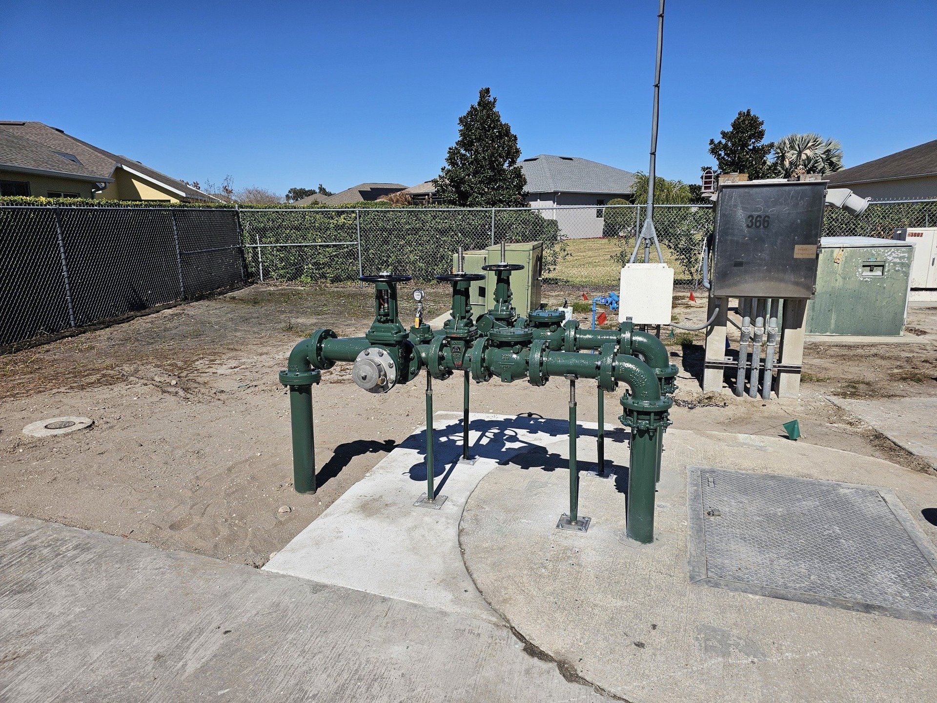 Green industrial water or irrigation pipeline system mounted on concrete foundation in an outdoor yard
