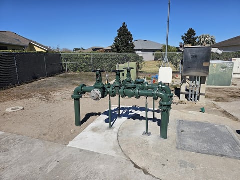 Green industrial water or irrigation pipeline system mounted on concrete foundation in an outdoor yard